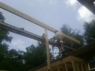 Carpenter setting a ridge beam over a new addition frame — Ice Dam Removal by Roofing Brothers in Levels