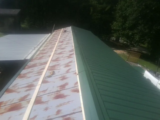 Old rusted panels beside newly installed green metal roofing — Wind Damage Roof Repair by Roofing Brothers in Levels
