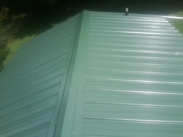 New green metal panels meeting at the ridge of a roof — Flat Roof Repair work by our crew in Levels