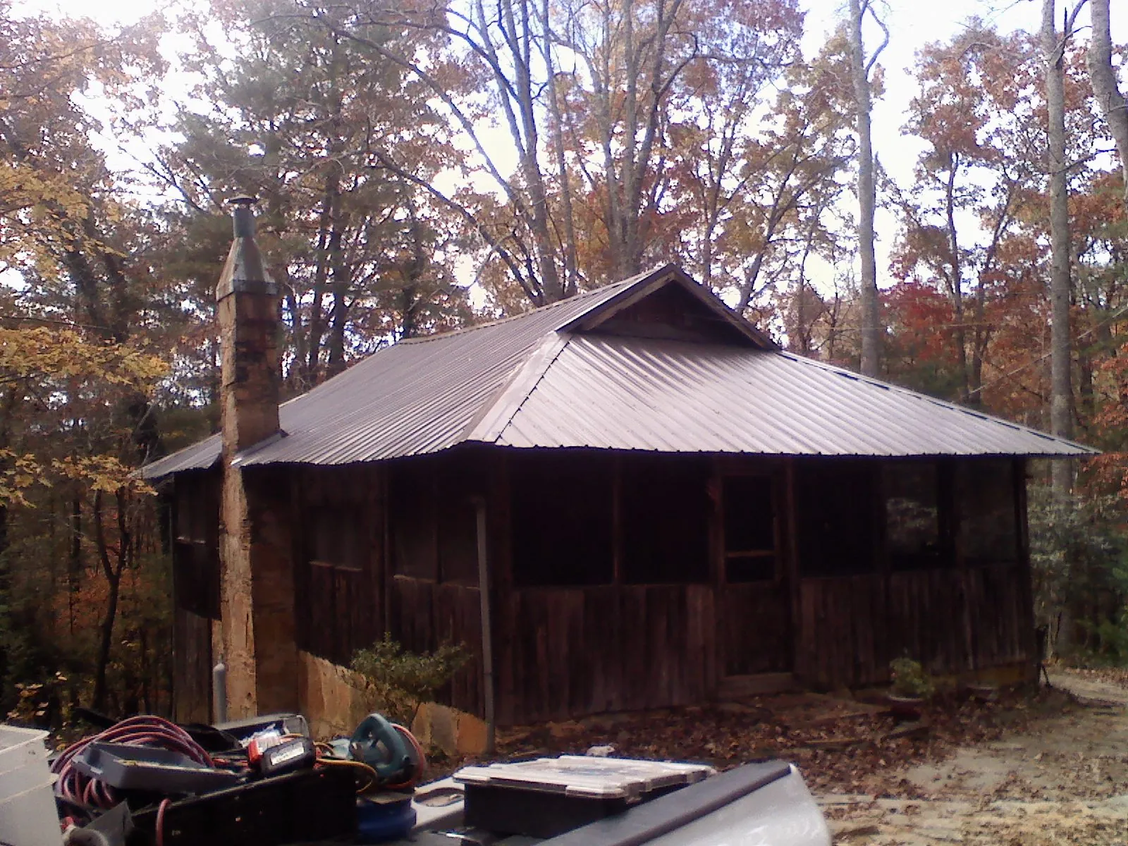 Brown metal hip roof on an old cabin with a stone chimney in Levels