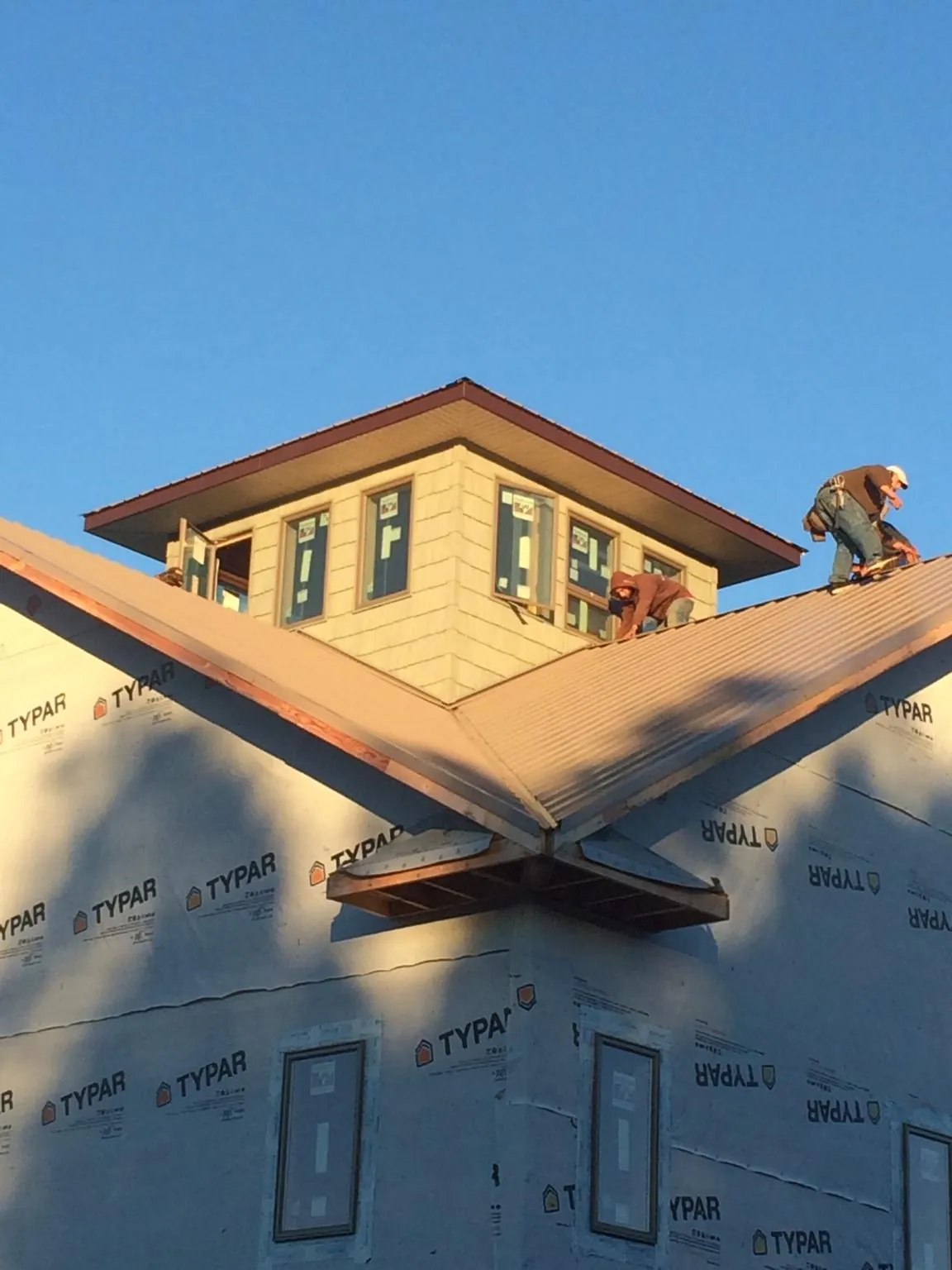 Roofers working around a rooftop cupola on a new metal roof at sunset — Roof Waterproofing in Levels by Roofing Brothers